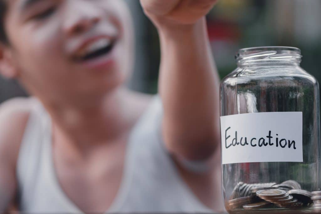 A child smiles behind a jar of coins with a label marked 