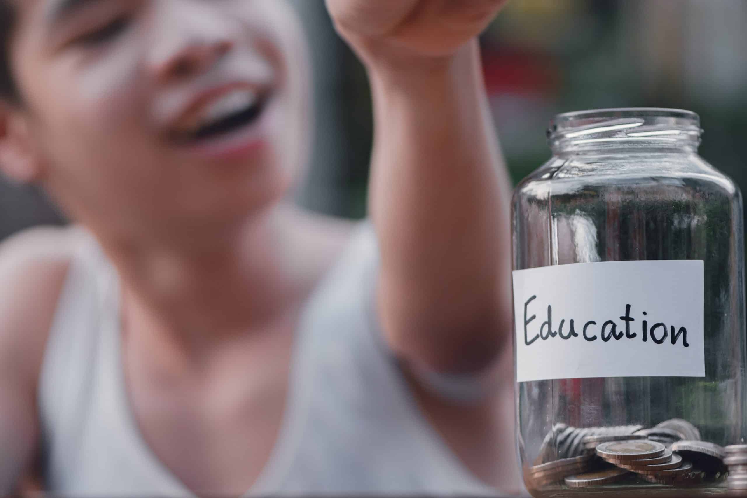 A child smiles behind a jar of coins with a label marked "Education"