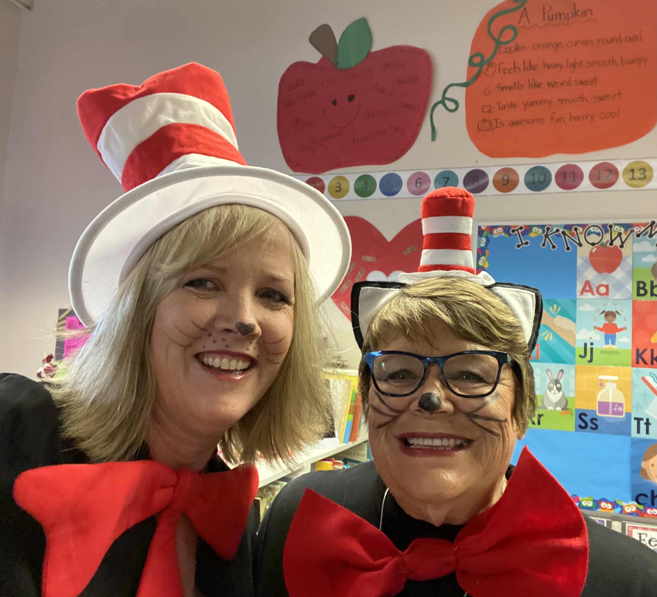 Two women smile while wearing Cat in the Hat costumes from the book by Dr Seuss