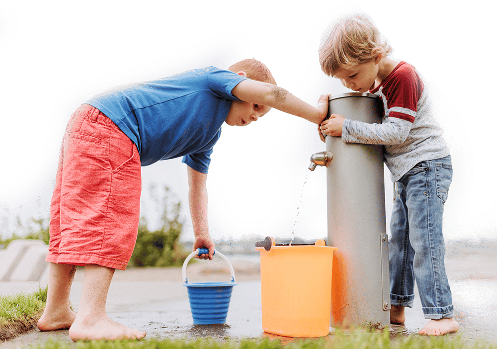Two kids play at a water pump