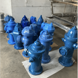 About a dozen fire hydrants sit in a room drying after bring painted blue.