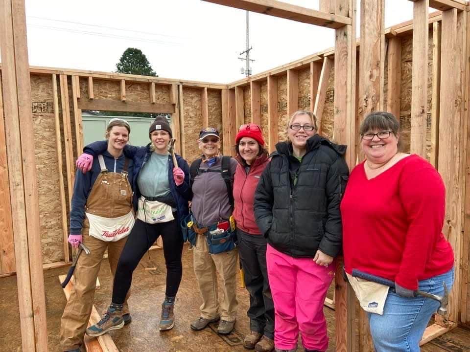 6 people stand inside a framed home under construction