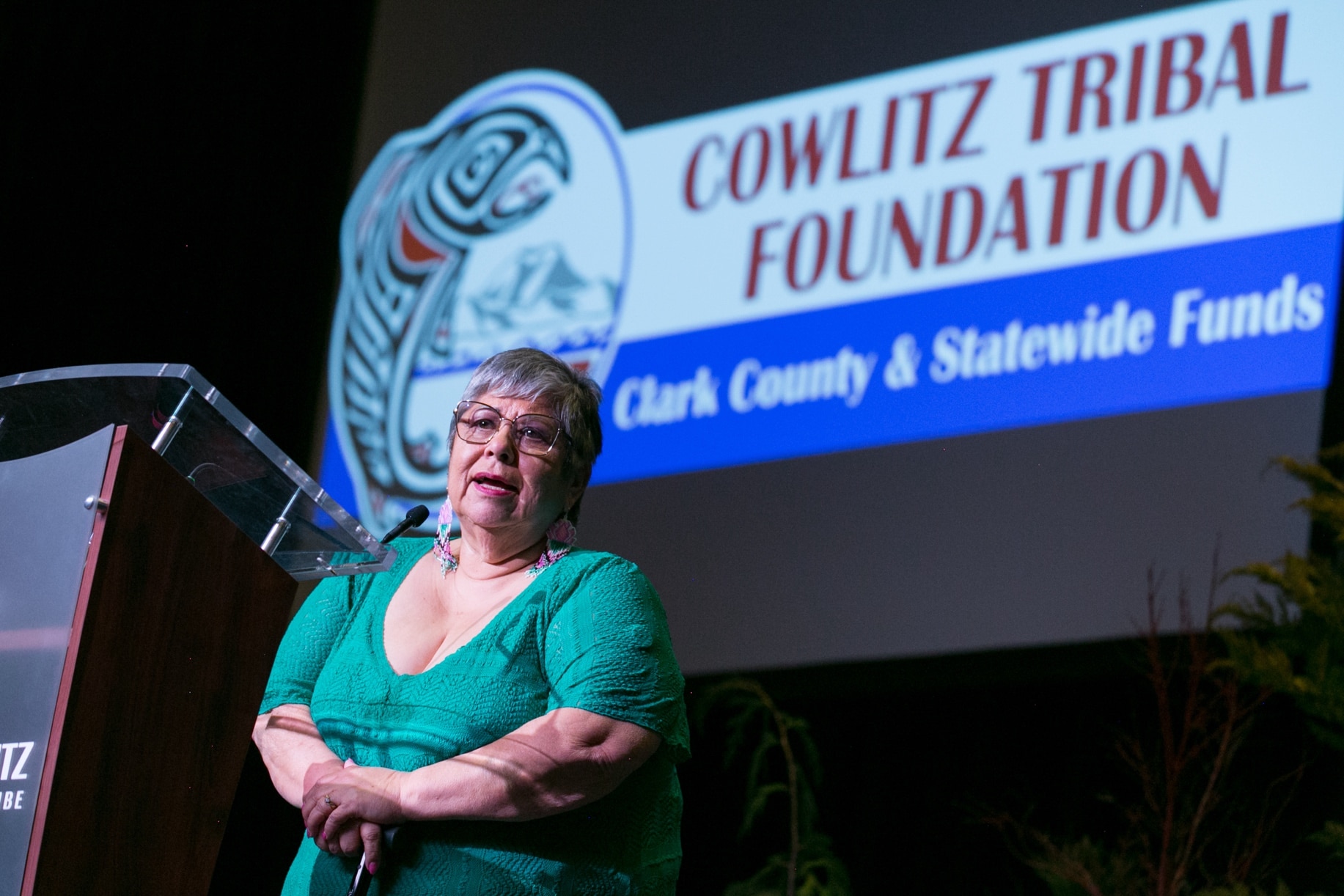 A woman speaks on stage in front of a sign that says Cowlitz Tribal Foundation