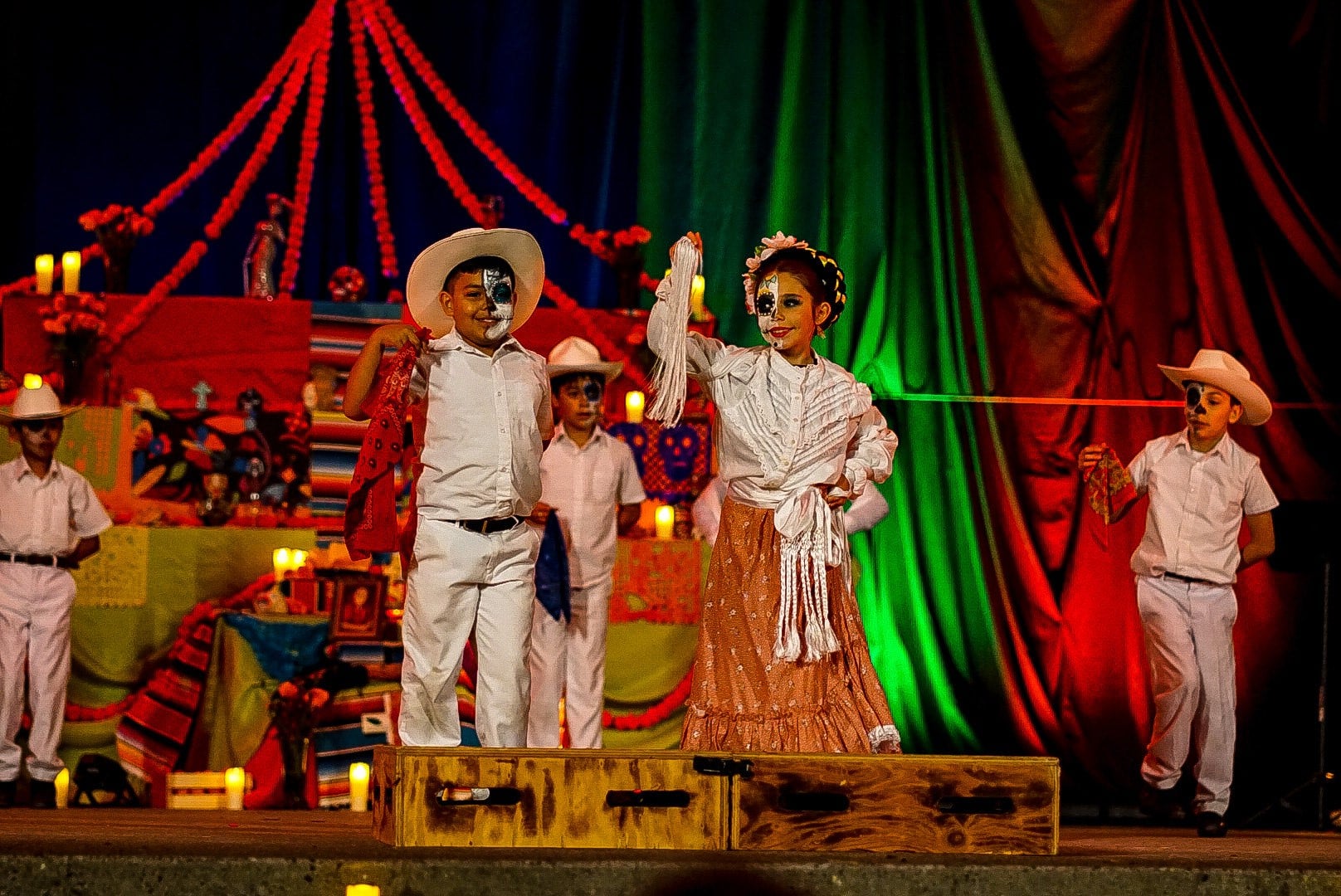 5 kids perform on stage wearing skeleton makeup for Día de los Muertos