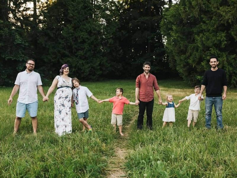 4 adults and 4 kids hold hands in a grass field