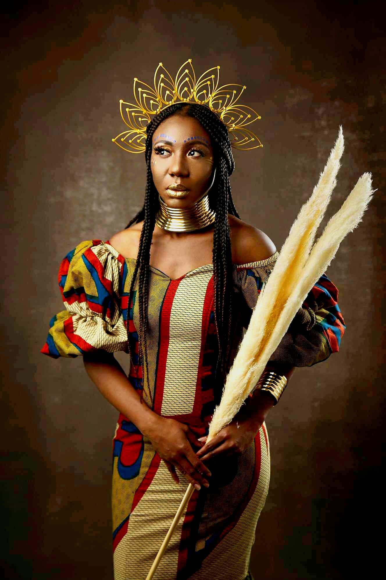 A Black woman wears African-inspired clothing and a gold crown
