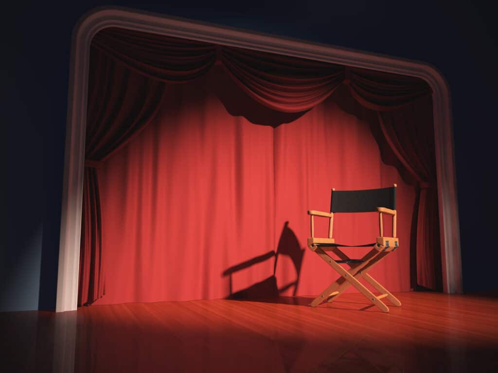 A directors chair on a stage with a red curtain behind it