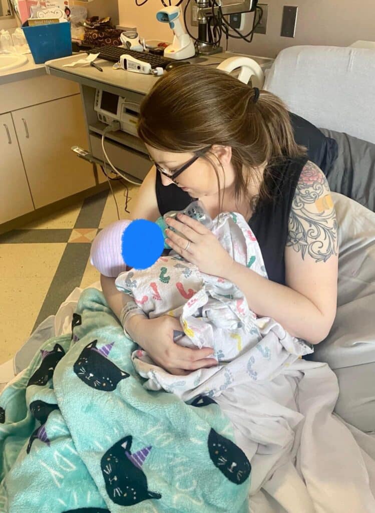 A woman feeds a baby with a bottle in a hospital room