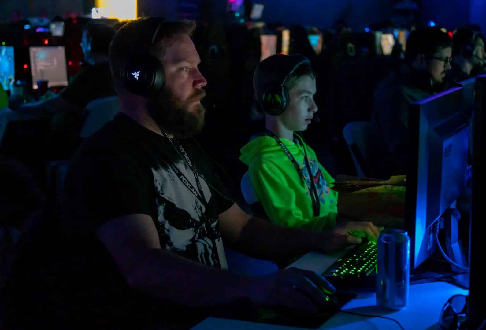 A father and son play video games on PCs