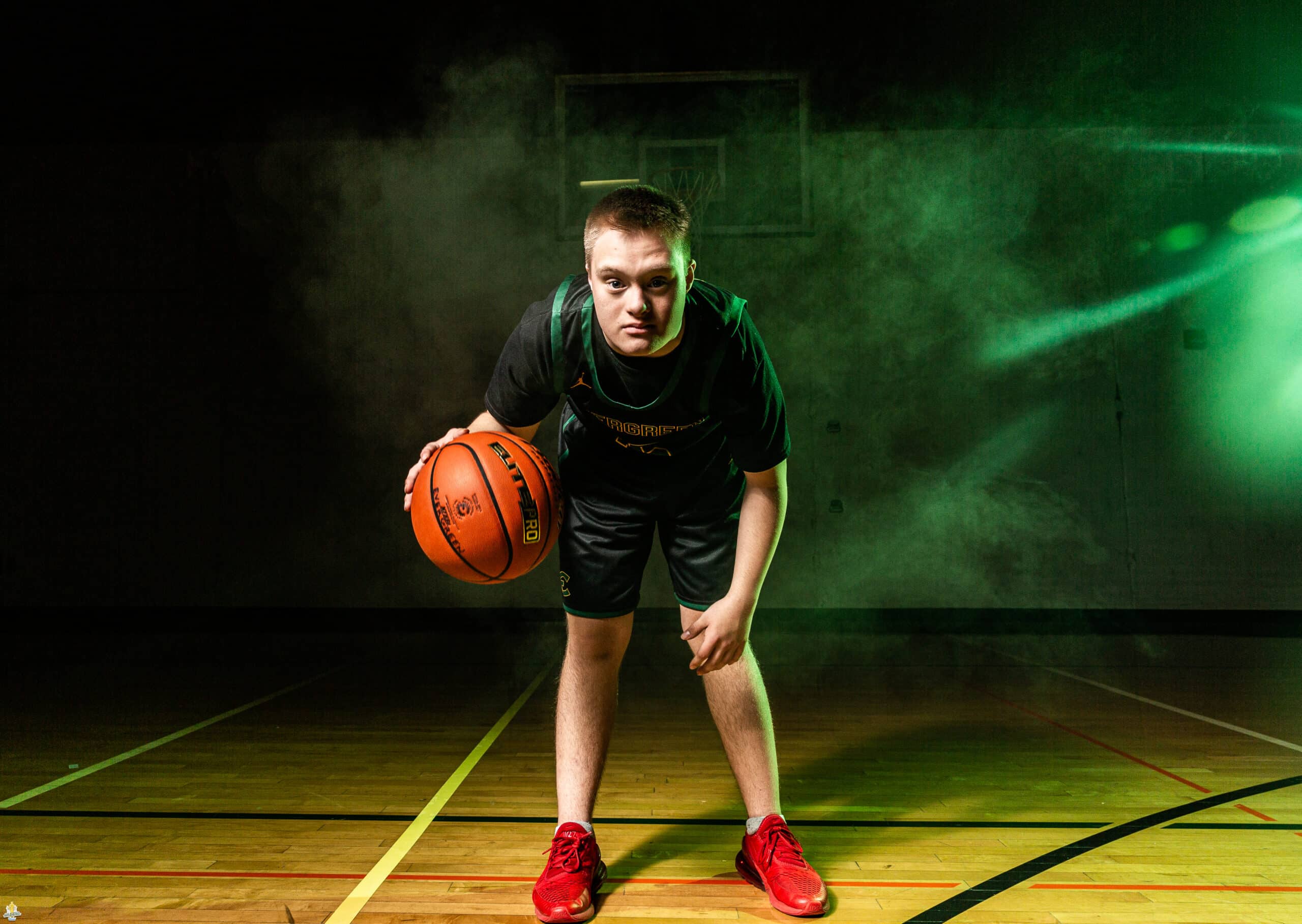 A basketball player with Down syndrome poses with a basketball on a court