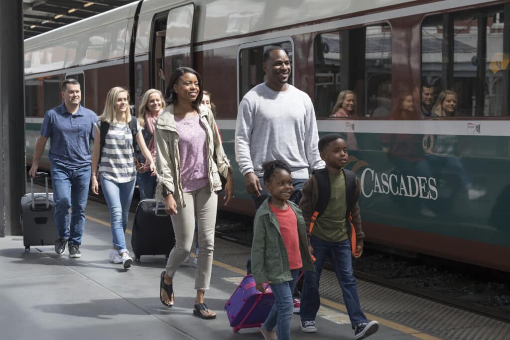 A family walks next to an Amtrak Cascades train