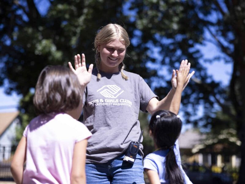 A teen girl gives kids high fives