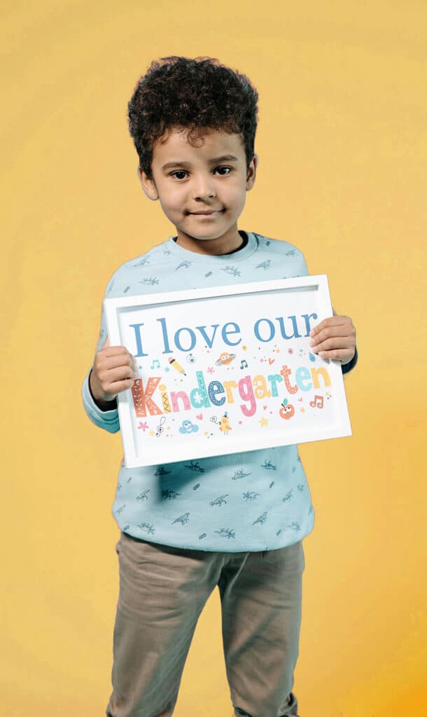 Kindergarten Age Cutoff - A boy holds a sign that says I love our kindergarten