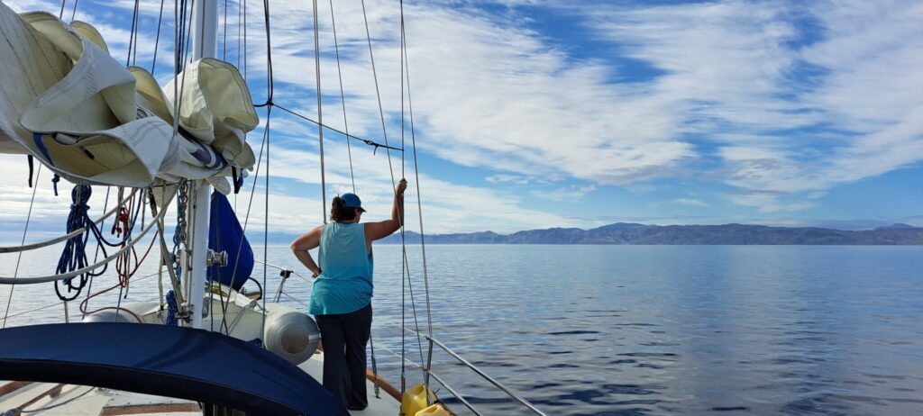 A woman stands on a boat overlooking the ocean