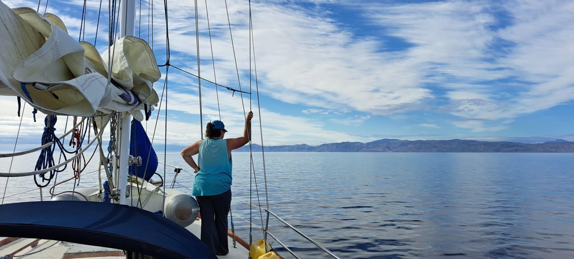 A woman stands on a boat overlooking the ocean