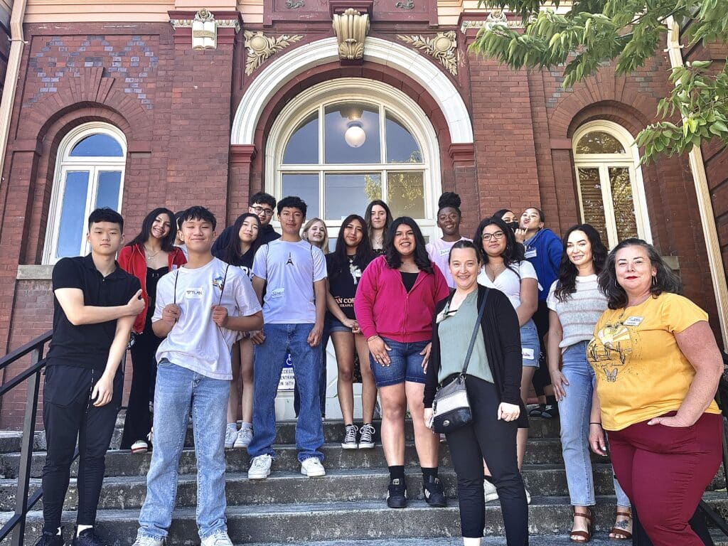 Leadership Clark County: students and adults pose in front of Clark County Historical Museum, a red brick building. 