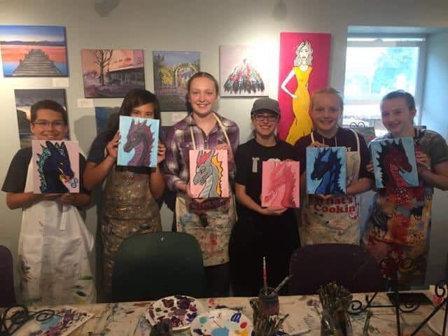 Teens pose with their paintings of dragons. Art Spaces in Vancouver.