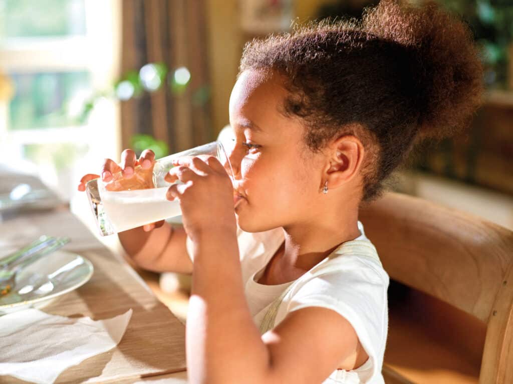 keeping kids hydrated - a girl drinks a glass of water